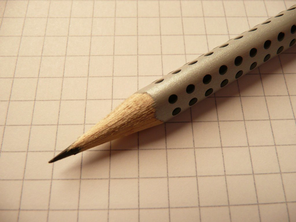 Crayon posé sur un cahier à petits carreaux, pour les exercices de grammaire